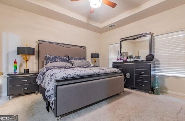 carpeted bedroom with a tray ceiling and ceiling fan