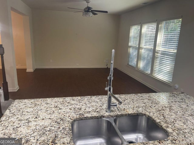 interior details featuring ceiling fan, light stone counters, sink, and dark hardwood / wood-style flooring