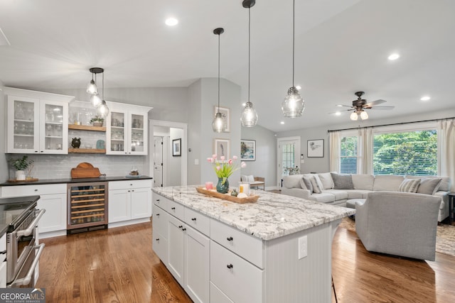 kitchen with pendant lighting, white cabinets, beverage cooler, and lofted ceiling