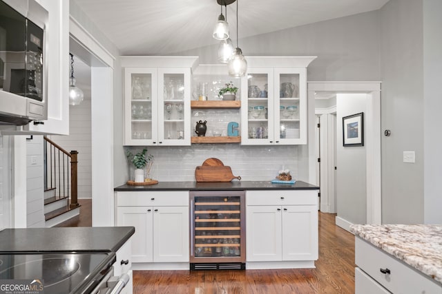 kitchen with lofted ceiling, dark stone counters, white cabinets, wine cooler, and stainless steel appliances