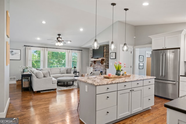 kitchen featuring white cabinets, lofted ceiling, hanging light fixtures, and high end refrigerator