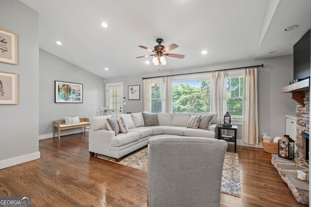 living room featuring a fireplace, vaulted ceiling, ceiling fan, and dark wood-type flooring