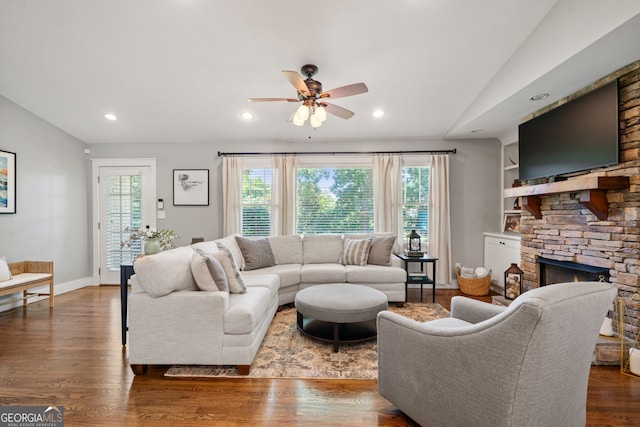 living room featuring ceiling fan, a fireplace, dark wood-type flooring, and vaulted ceiling