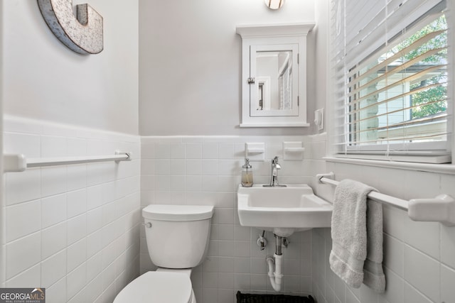 bathroom with toilet, tile walls, and sink