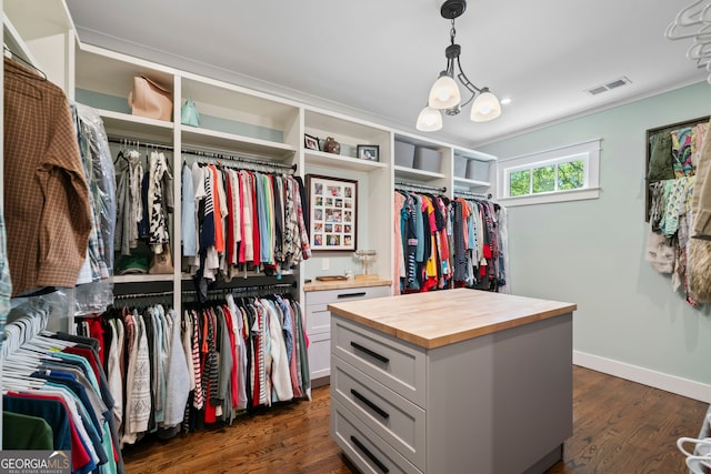 spacious closet with a notable chandelier and dark wood-type flooring