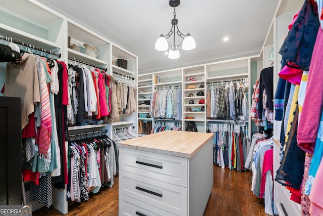 walk in closet with a notable chandelier and dark wood-type flooring