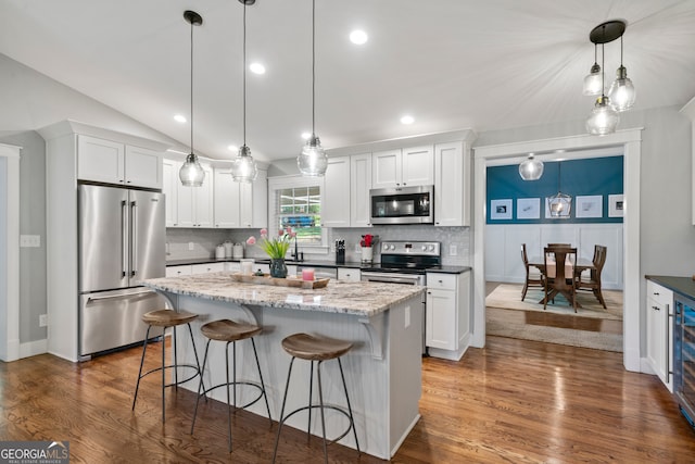 kitchen with white cabinets, appliances with stainless steel finishes, a kitchen island, and hanging light fixtures