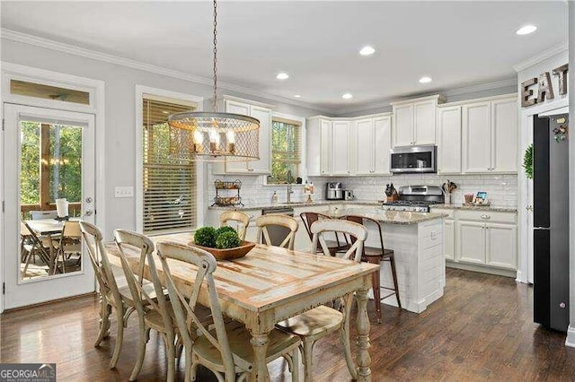 kitchen with light stone countertops, dark hardwood / wood-style flooring, hanging light fixtures, stainless steel appliances, and white cabinets