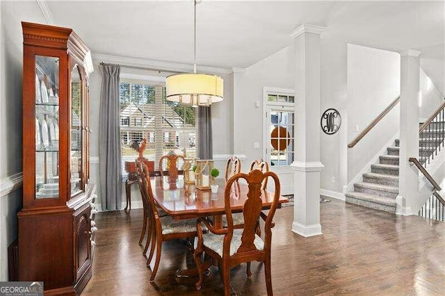 dining area featuring dark wood-type flooring, ornate columns, and crown molding