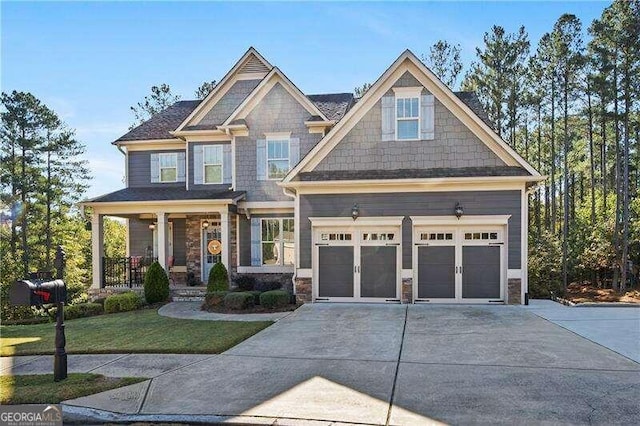 craftsman inspired home featuring a porch, a front lawn, and a garage