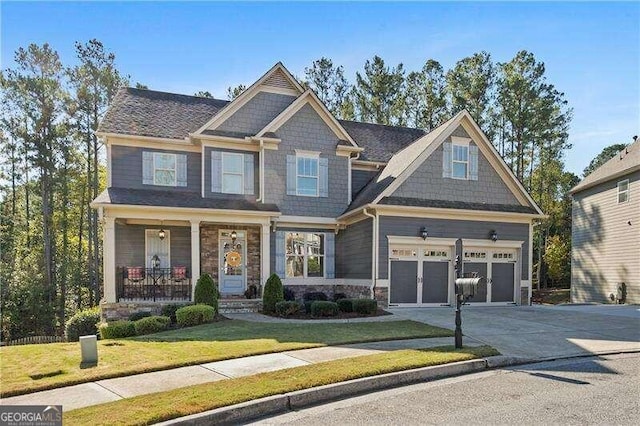 craftsman-style home featuring covered porch, a front yard, and a garage