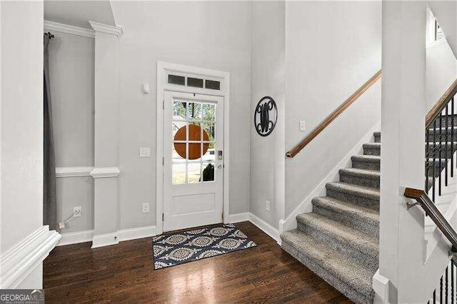 foyer with ornamental molding and dark hardwood / wood-style flooring