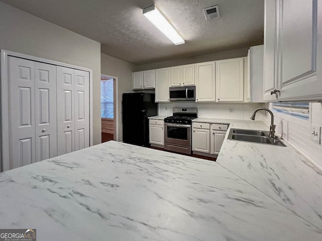 kitchen with white cabinets, stainless steel appliances, sink, and a textured ceiling