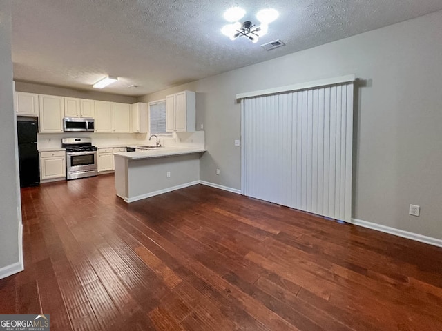 kitchen featuring kitchen peninsula, white cabinets, stainless steel appliances, and dark wood-type flooring