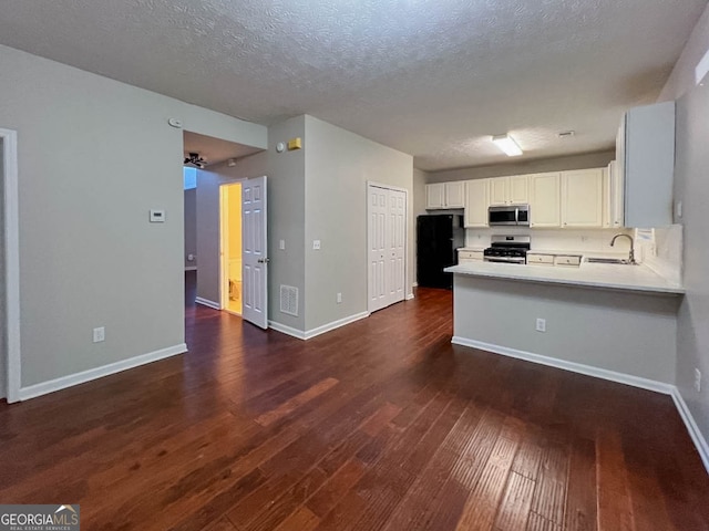 kitchen featuring dark wood-type flooring, kitchen peninsula, stainless steel appliances, white cabinets, and a textured ceiling