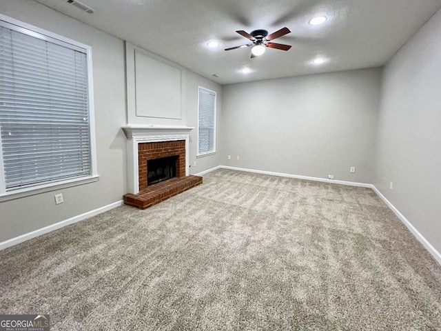 unfurnished living room with ceiling fan, carpet floors, and a fireplace