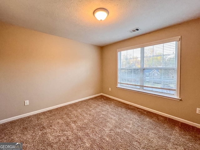 empty room with a textured ceiling and carpet flooring