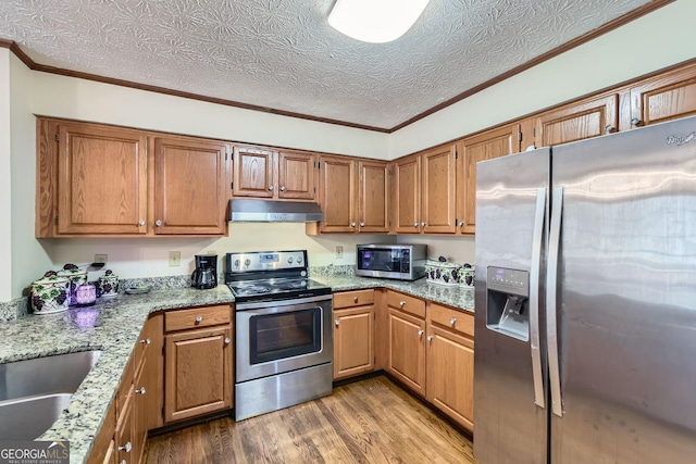 2582 Fairview Ln, Jonesboro, GA 30236 - kitchen featuring crown molding, under cabinet range hood, light stone counters, appliances with stainless steel finishes, and wood finished floors