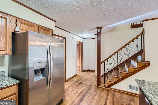 2582 Fairview Ln, Jonesboro, GA 30236 - kitchen with visible vents, light wood-style flooring, crown molding, and stainless steel fridge with ice dispenser