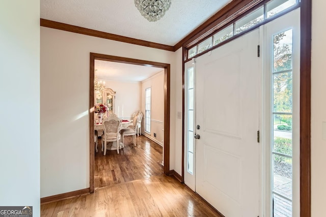 2582 Fairview Ln, Jonesboro, GA 30236 - foyer entrance featuring a chandelier, light wood-type flooring, ornamental molding, plenty of natural light, and a textured ceiling