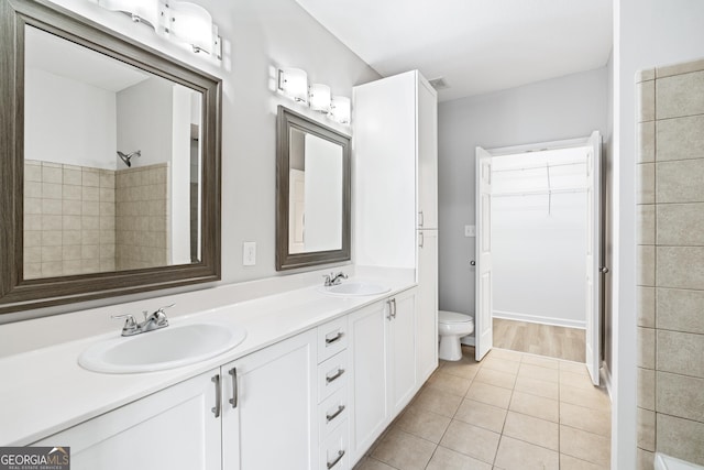 bathroom with tile patterned flooring, vanity, toilet, and a tile shower