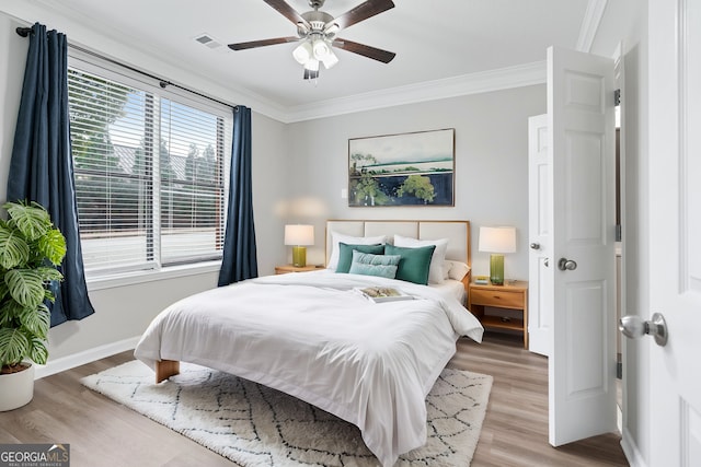 bedroom featuring ceiling fan, light hardwood / wood-style floors, and crown molding