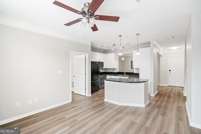 kitchen featuring black fridge, sink, hanging light fixtures, light wood-type flooring, and white cabinetry