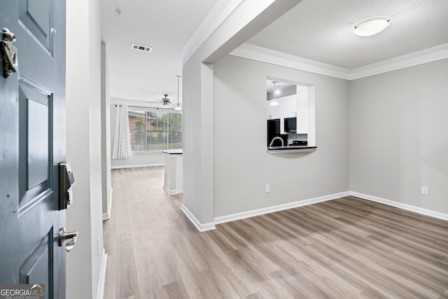 interior space with crown molding, a textured ceiling, and light wood-type flooring