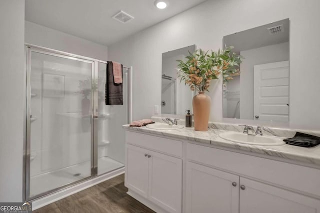 bathroom with hardwood / wood-style flooring, vanity, and a shower with shower door