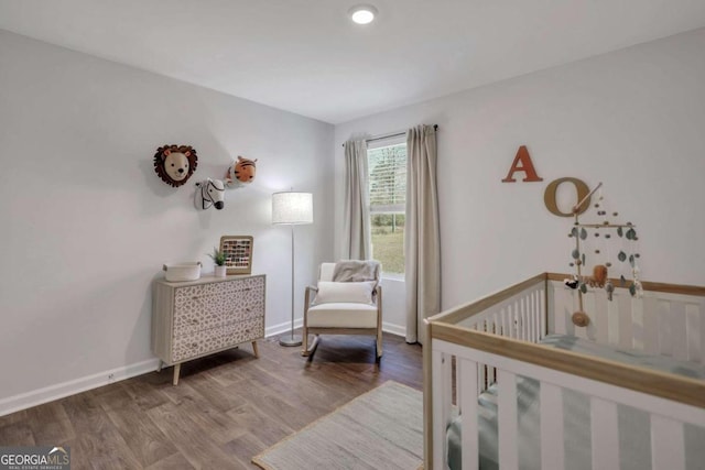 bedroom with a crib and wood-type flooring