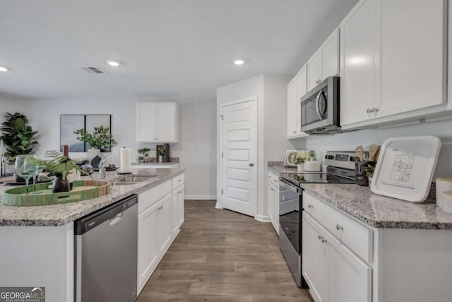 kitchen with sink, white cabinetry, dark hardwood / wood-style flooring, stainless steel appliances, and light stone countertops