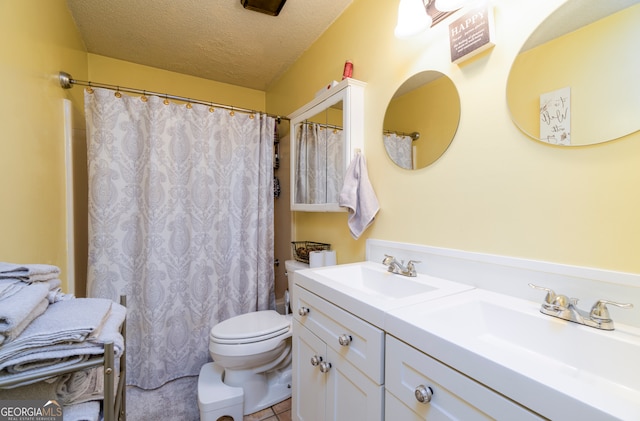 bathroom featuring vanity, tile patterned flooring, a textured ceiling, and toilet