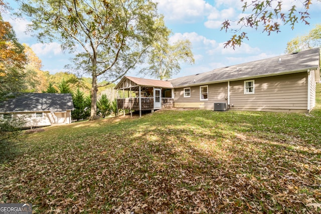 back of property featuring a wooden deck, central AC, and a yard