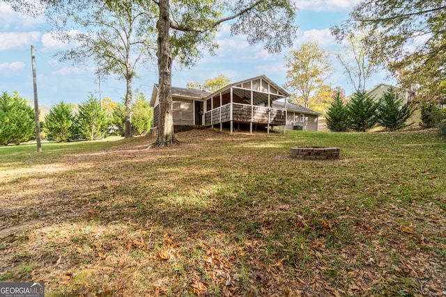 rear view of house featuring an outdoor fire pit, a lawn, a sunroom, and a deck