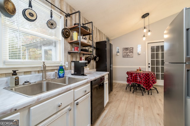 kitchen featuring decorative light fixtures, light hardwood / wood-style flooring, lofted ceiling, stainless steel fridge, and black dishwasher