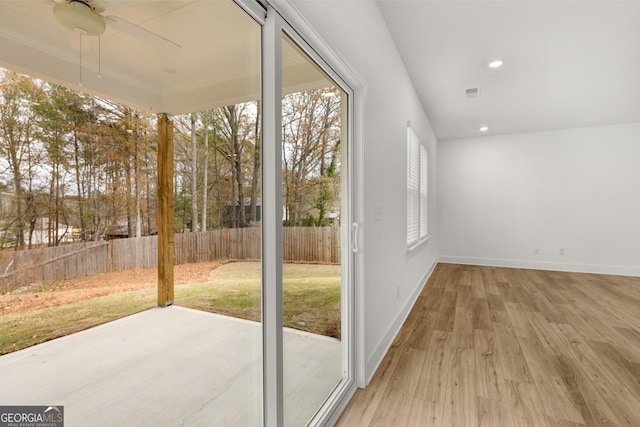 doorway with hardwood / wood-style flooring, ceiling fan, and crown molding