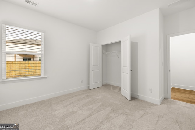 unfurnished bedroom with a closet and light colored carpet