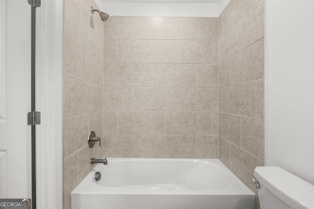 bathroom featuring toilet and tiled shower / bath