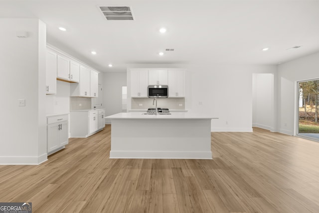 kitchen featuring white cabinetry, light hardwood / wood-style flooring, and an island with sink