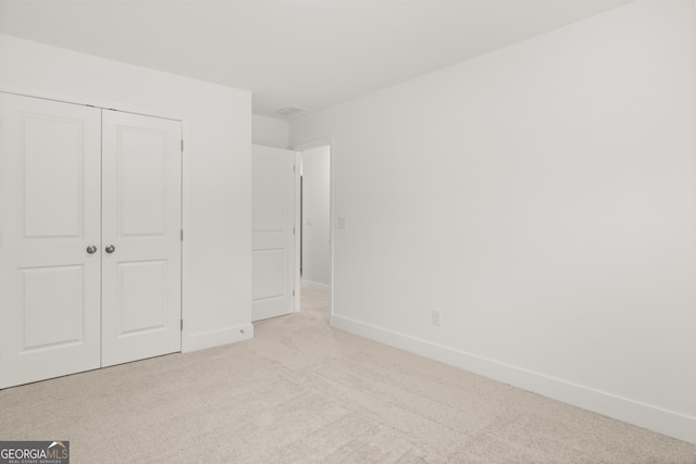 unfurnished bedroom with light carpet and a closet