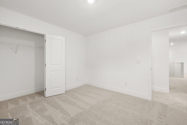 unfurnished bedroom featuring light carpet and a closet