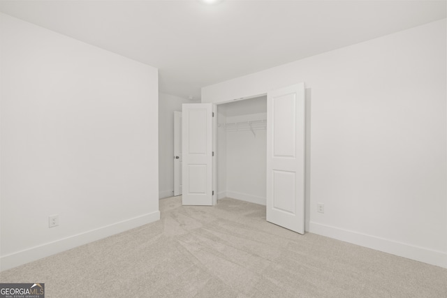 unfurnished bedroom featuring light colored carpet and a closet