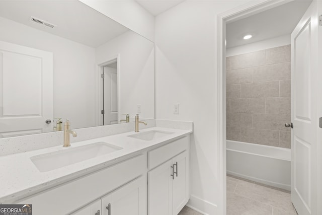 bathroom featuring tile patterned flooring, vanity, and tiled shower / bath