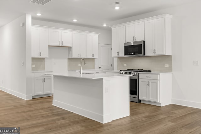 kitchen featuring a center island with sink, sink, white cabinetry, and stainless steel appliances