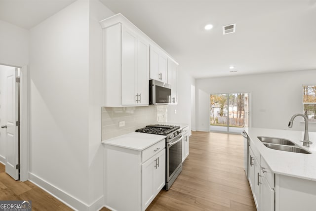 kitchen with sink, a healthy amount of sunlight, light wood-type flooring, and appliances with stainless steel finishes