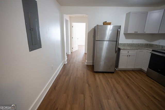 kitchen featuring appliances with stainless steel finishes, dark hardwood / wood-style flooring, light stone counters, white cabinets, and electric panel