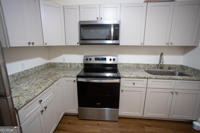 kitchen featuring white cabinetry, sink, light stone counters, dark hardwood / wood-style floors, and appliances with stainless steel finishes