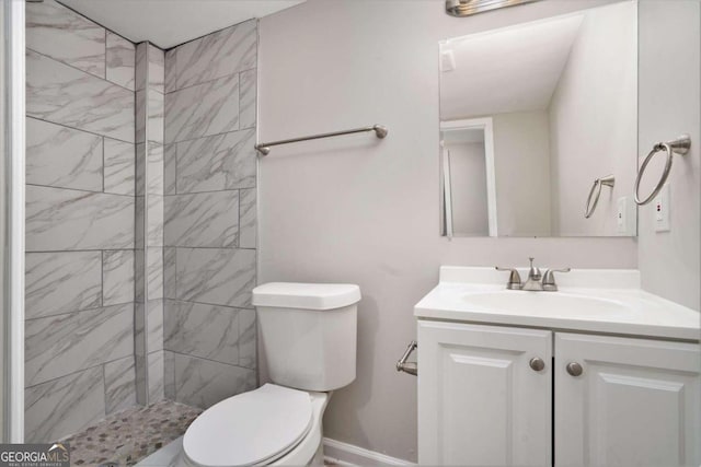 bathroom featuring vanity, tiled shower, and toilet