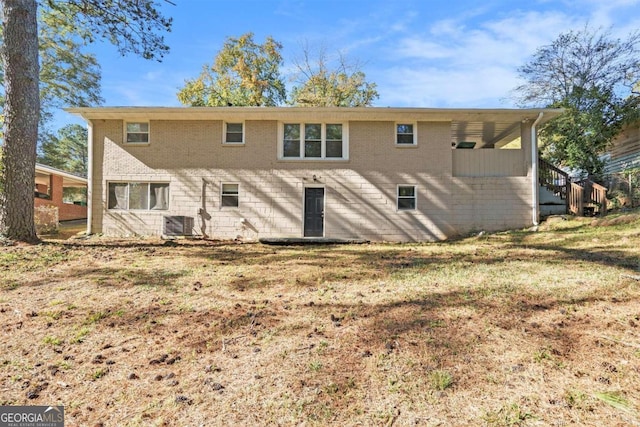 rear view of house featuring central air condition unit and a yard