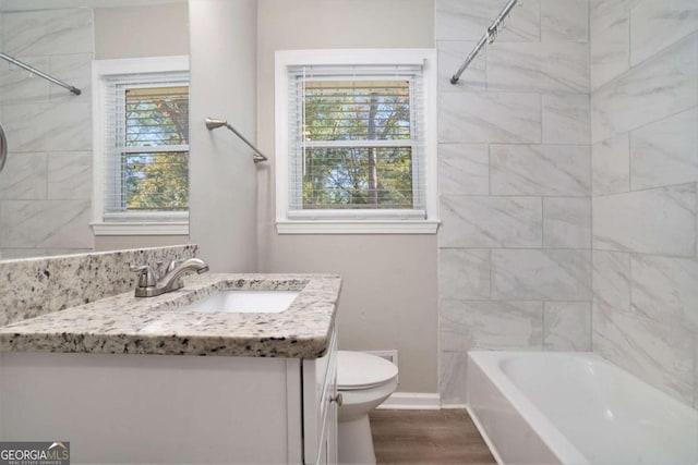 full bathroom featuring vanity, toilet, a healthy amount of sunlight, and wood-type flooring